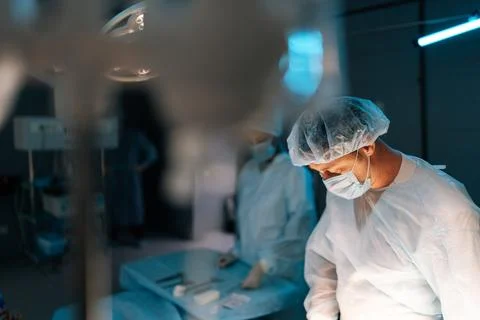 Selective focus of cooperating team of surgeons processing surgical operation in Stock Photos