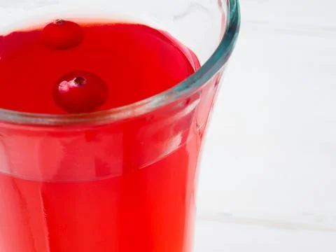 Selective focus on cranberries floating in a fresh drink in a glass cup Stock Photos