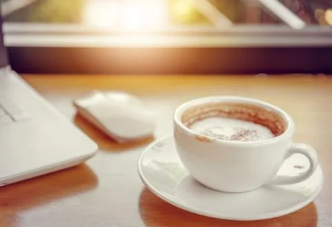 Selective focus, Cup of coffee latte art in coffee shop with blurred laptop 스톡 사진