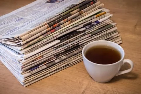 Selective focus of the cup of tea stacking newspapers folded place on wooden Stock Photos