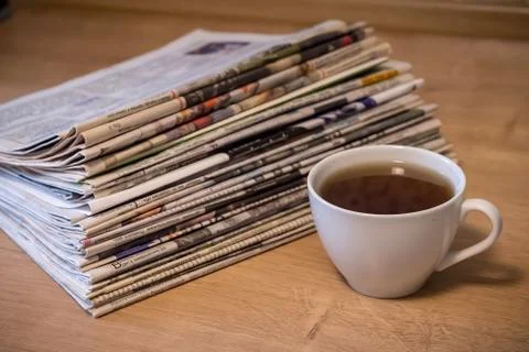 Selective focus of the cup of tea stacking newspapers folded place on wooden Stock Photos