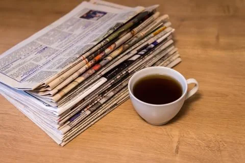 Selective focus of the cup of tea stacking newspapers folded place on wooden Stock Photos