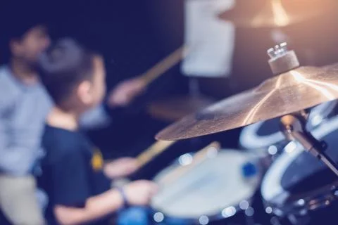 Selective focus to cymbals of drum set with blurry kid learning and play drum Stock Photos