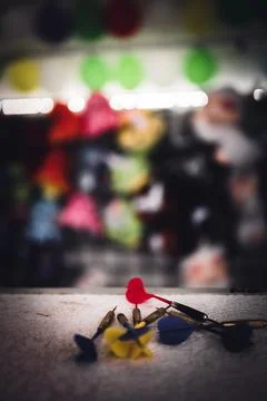Selective focus on darts sitting on a ledge with a wall of balloon targets and Foto stock