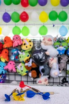 Selective focus on darts sitting on a ledge with a wall of balloon targets and Foto stock