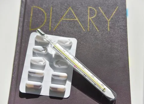 Selective focus of the diary with thermometer and pills on the background Stock Photos