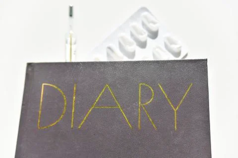 Selective focus of the diary with thermometer and pills on the background Stock Photos