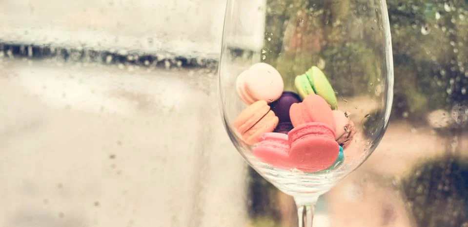In selective focus of Different types of macaroons in motion in big wine glas Foto stock