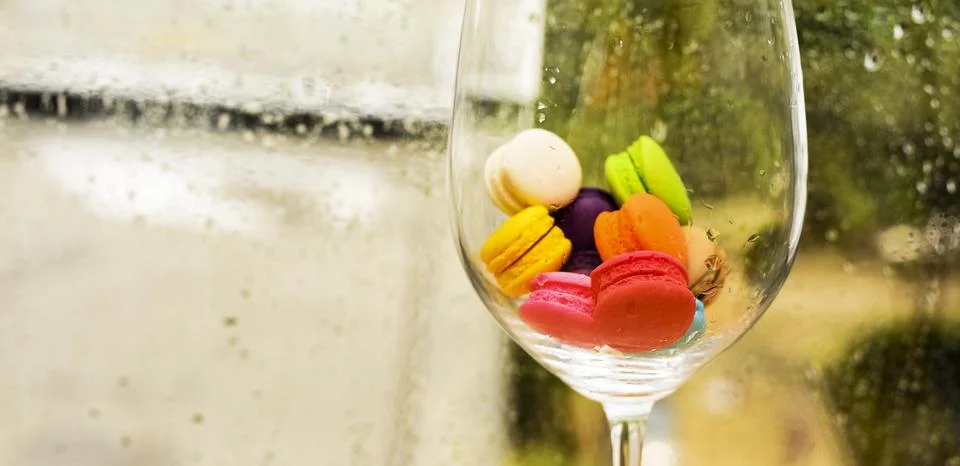 In selective focus of Different types of macaroons in motion in big wine glas Stock Photos
