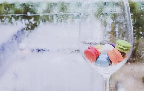 In selective focus of Different types of macaroons in motion in big wine glas Stock Photos