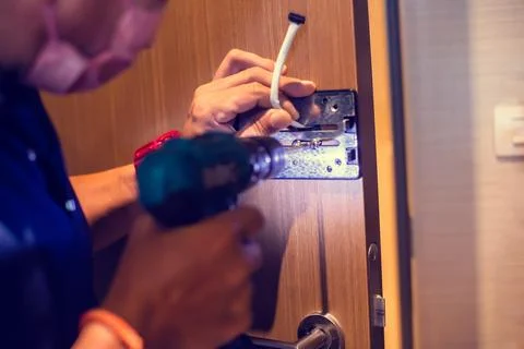 Selective focus to digital door lock pad with blurry hand of a mechanic. Stock Photos