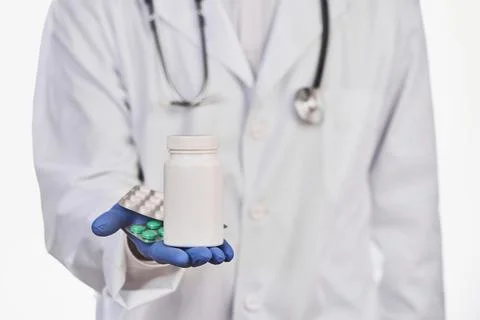 Selective focus on doctor's hand with a bottle and blister of pills Stock Photos