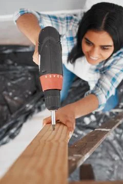 Selective focus on drill with young Indian woman drills into wood- overhead shot Stock Photos