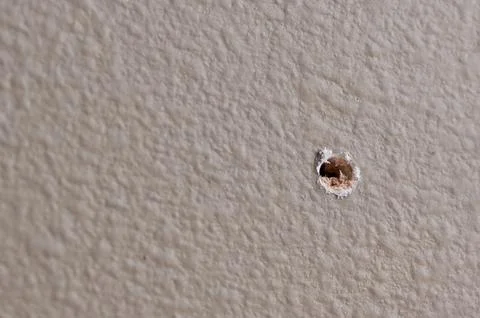 Selective focus on drilled hole through drywall with bits of insulation showing. Foto stock