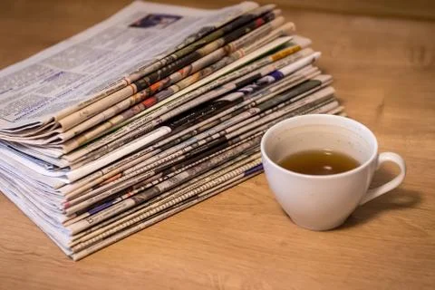 Selective focus of the drunk cup of tea stacking newspapers folded place on Stock Photos