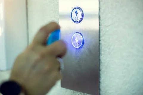 Selective focus to elevator switch button with blur hand of staff cleaning it Stockfoto's