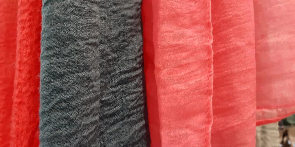 Selective focus. Fabric texture closeup . A row of scarfs hanging from rail Stock Photos