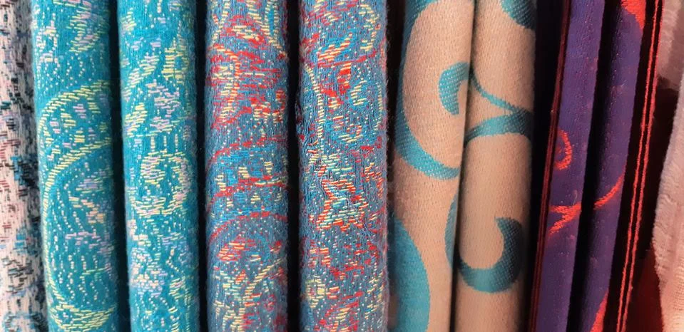 Selective focus. Fabric texture closeup . A row of scarfs hanging from rail Stock Photos