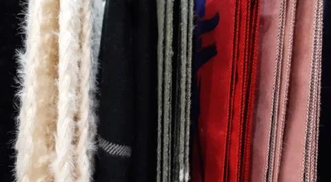 Selective focus. Fabric texture closeup . A row of scarfs hanging from rail Stock Photos