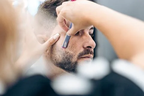 Selective focus on the face of a costumer being shaved by hand with a razor Stock Photos