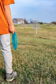Selective focus fairway grass with a defocused young child holding a putter disc Foto stock