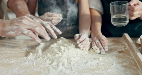 Selective focus family hands kneading dough on wooden surface pouring water Vídeo Stock 218630997