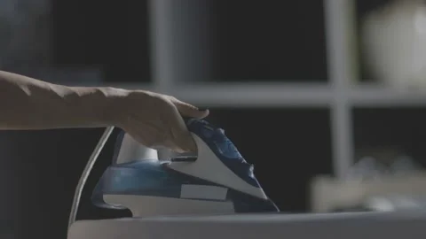 Selective focus of female hand irons white clothes with steam iron on an Ironing Stock Footage 235280258
