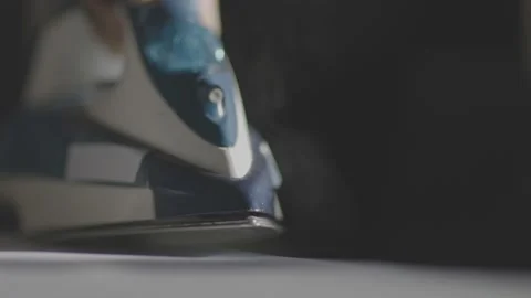 Selective focus of female hand irons white clothes with steam iron on an Ironing Stock Footage 235280329