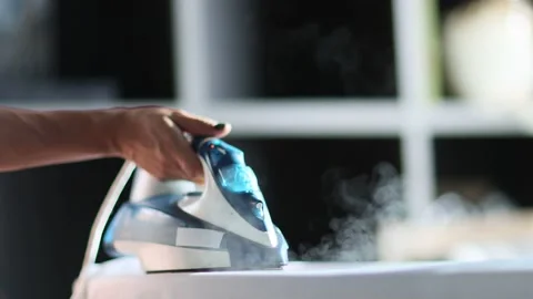Selective focus of female hand irons white clothes with steam iron on an Ironing Stock Footage 235280442