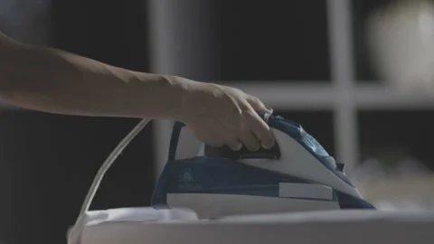 Selective focus of female hand irons white clothes with steam iron on an Ironing Stock Footage 235671494