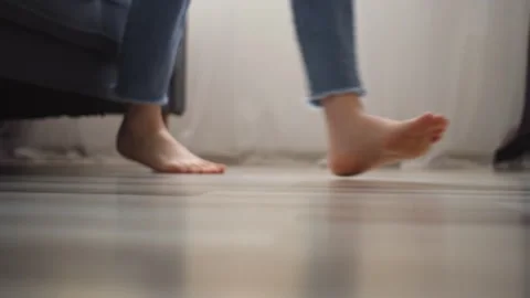 Selective focus of female legs walking barefoot on wooden warm floor near couch Vidéo 265138638