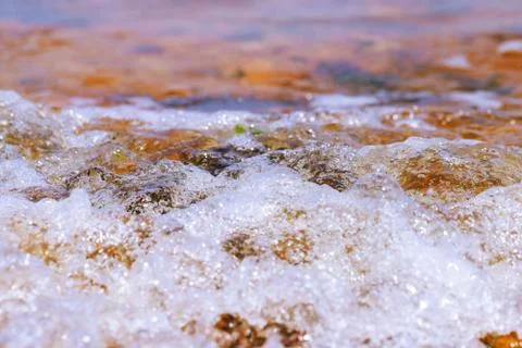 Selective focus foaming water on ocean shore. Stock Photos
