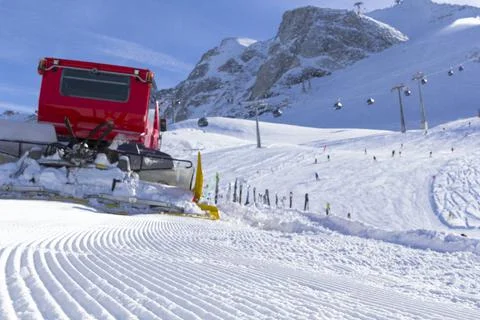 Selective focus to the fore. Snowplow clears tracks in the ski resort of the Stock Photos