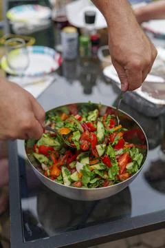 Selective focus of fresh chopped spring salad, man mixing salad, backyard Stock Photos