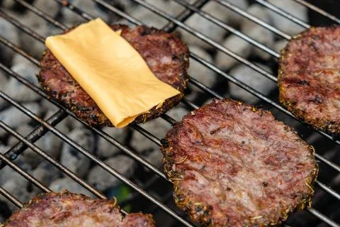 Selective focus of fresh delicious burger cutlets with cheese grilling on bbq Stock Photos