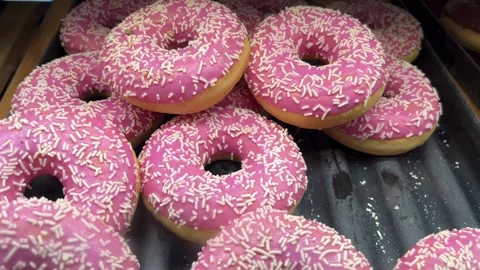 Selective focus freshly glazed pink donuts displayed on supermarket shelf Stock Footage 344954857