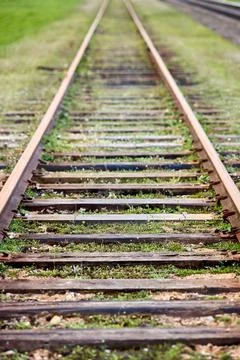 Selective focus on going straight railway abandoned rusty, overgrown with grass Stock Photos