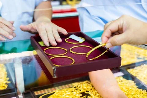 Selective focus to gold bangle in a red velvet tray  there customer is shoppi Stock Photos