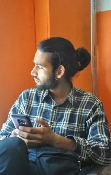 Selective focus of a good looking bearded man with hair bun, looking sideways  Foto stock