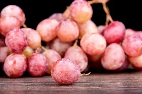 Selective focus. Grape berry and blurred bunch of red grapes. Stock Photos
