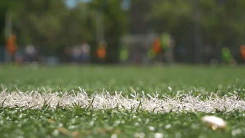 Selective focus to green artificial turf with blurry coach is coaching kid Stock Footage 147185114