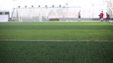 Selective focus to green artificial turf with blurry coach is coaching kid playe Stock Footage 149626612