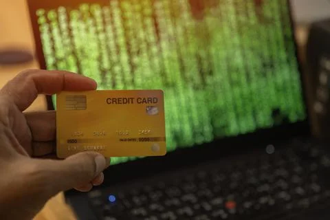 Selective focus of hacker hand holding a credit card and stolen data of onl.. Stock Photos