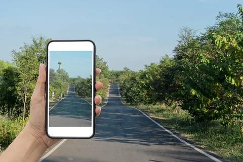 Selective focus of hand holding smartphone and take a photo of scenery. Stock Photos