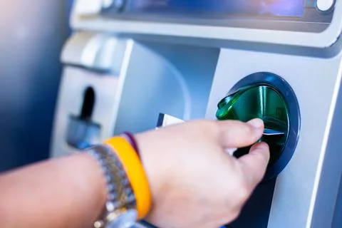 Selective focus to hand inserting a credit card in the ATM. Stock Photos