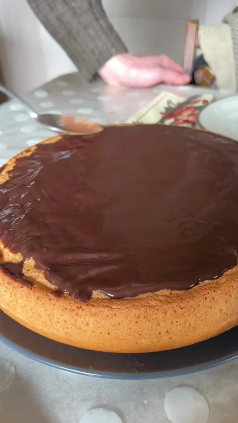 Selective focus hand spreading chocolate glaze on sponge cake Stockbeeldmateriaal 334328011