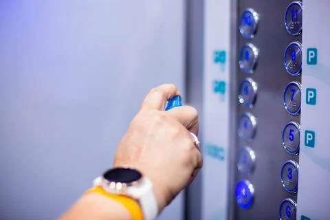 Selective focus to hand of staff cleaning elevator switch button with alcohol Stock Photos