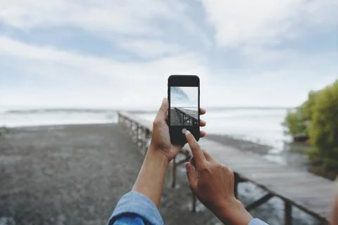 Selective focus on hand using smart phone taking landscape photo Stock Photos