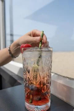 Selective focus on hand of a woman's hand with cocktail glass in which a red Stock-Fotos