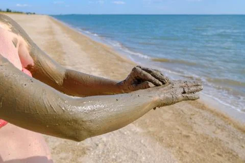 Selective focus on hands in curative mud on the background of the sea beach. Stock Photos